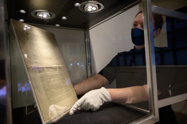 Un expert de la Sotheby's prezintă o pagină a primei Constituții înainte de licitație. ED JONES | Getty Images